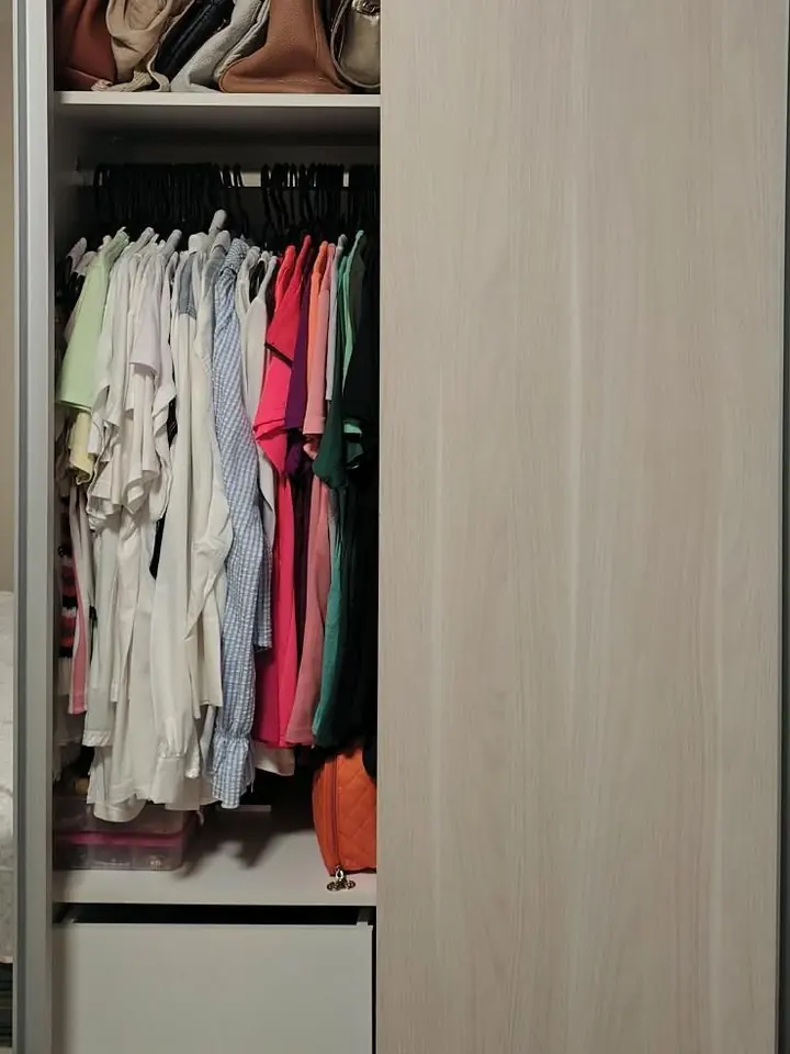 Armário com roupas penduradas e caixas organizadoras no alto