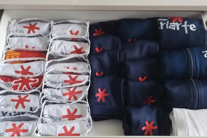 Gaveta com uniformes escolares enrolados em colmeias